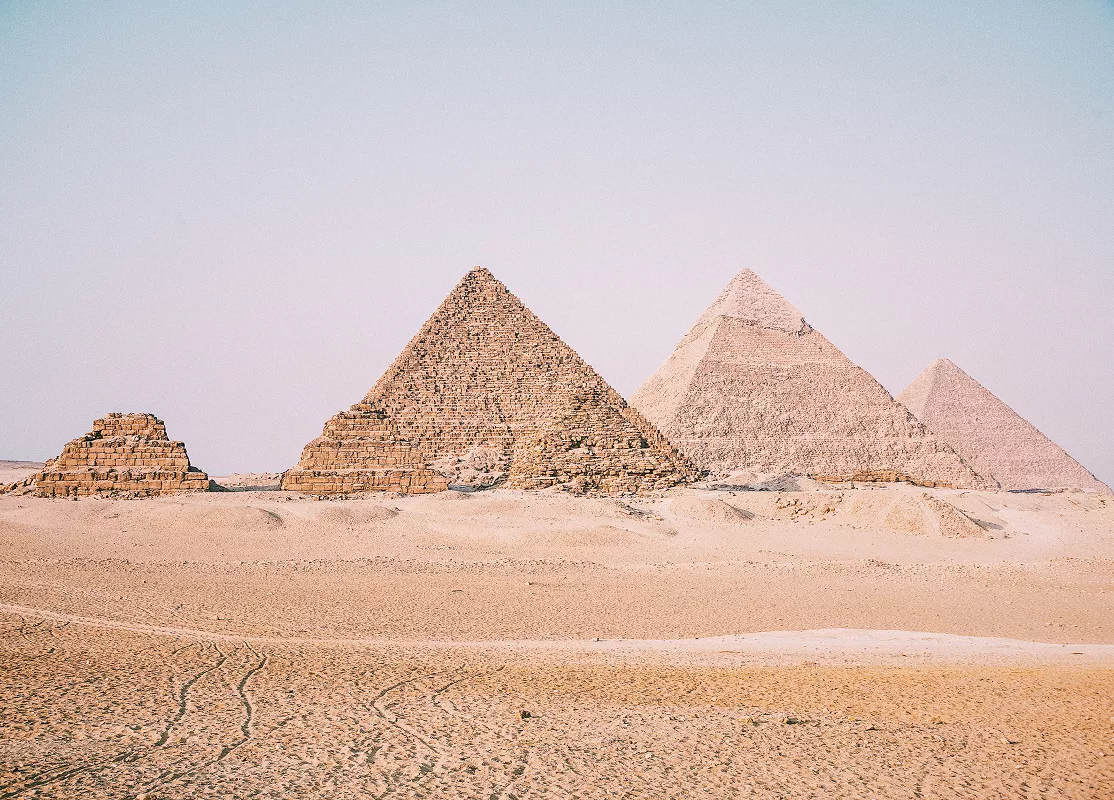 Two large pyramids stand majestically in a vast desert landscape under a clear blue sky.
